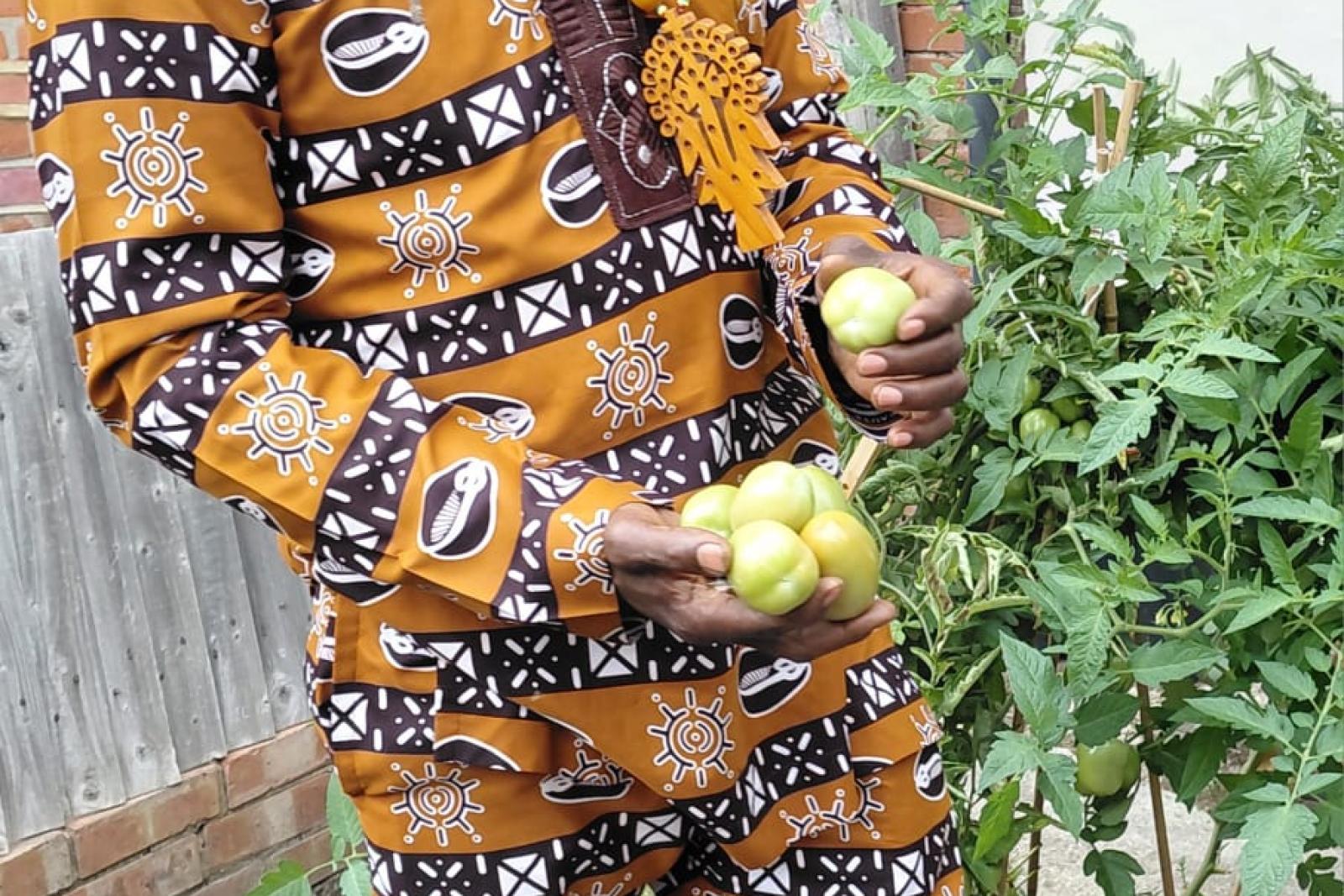 Fyah Mawi standing outdoors in a patterned suit and cap.