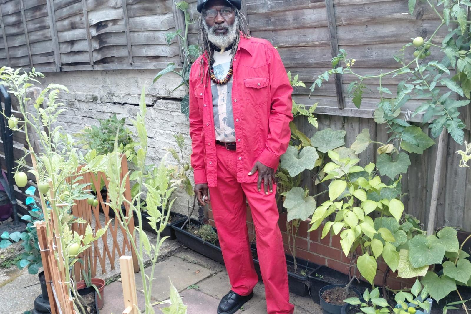Fyah Mawi wearing a bright red suit in a garden.
