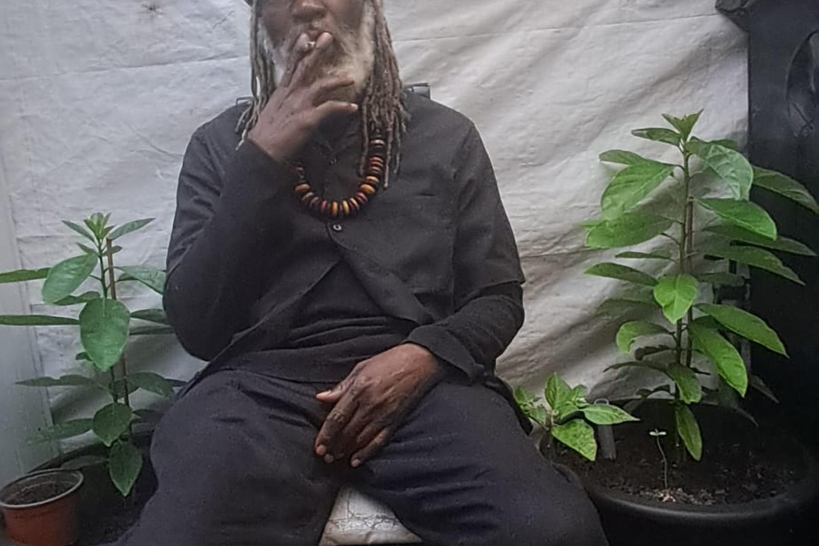 Fyah Mawi seated outdoors in a dark suit.