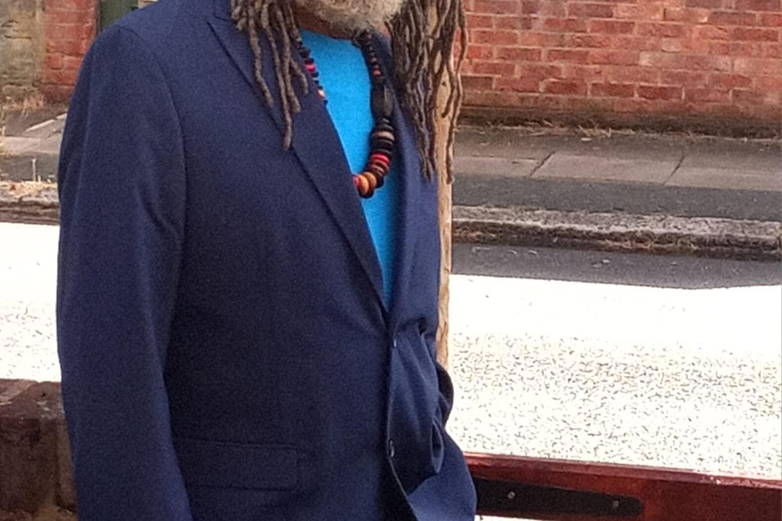 Portrait of Fyah Mawi wearing a blue suit and dark hat.