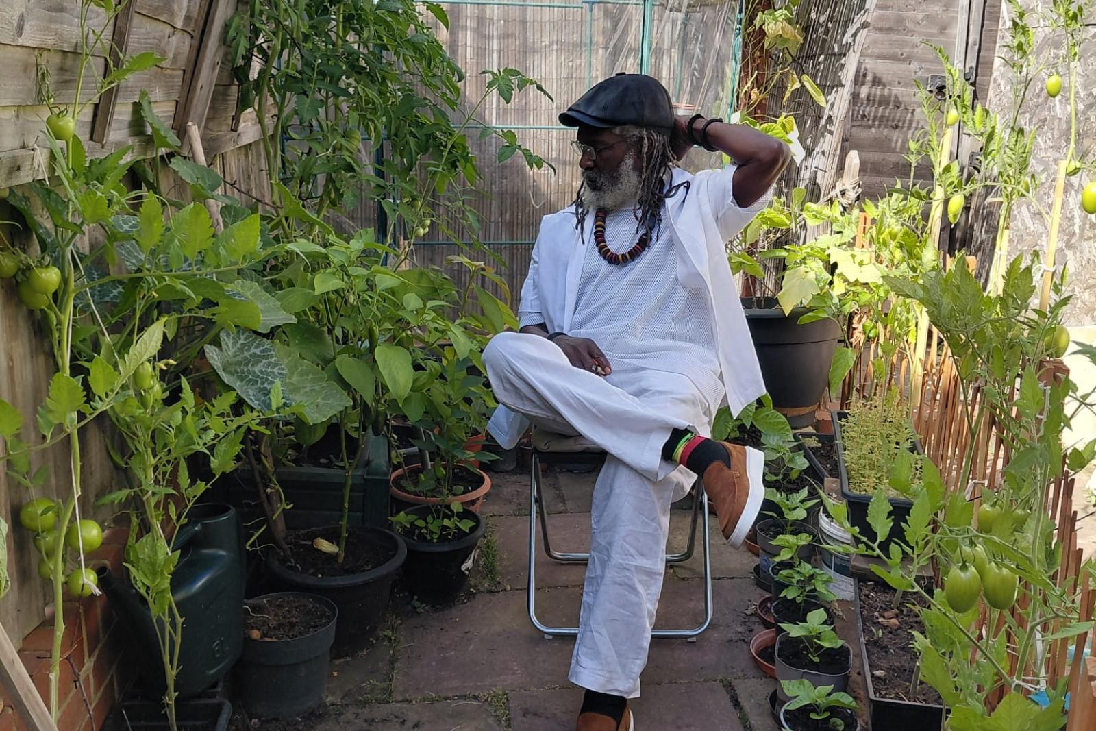 Fyah Mawi seated in a garden wearing a light suit.