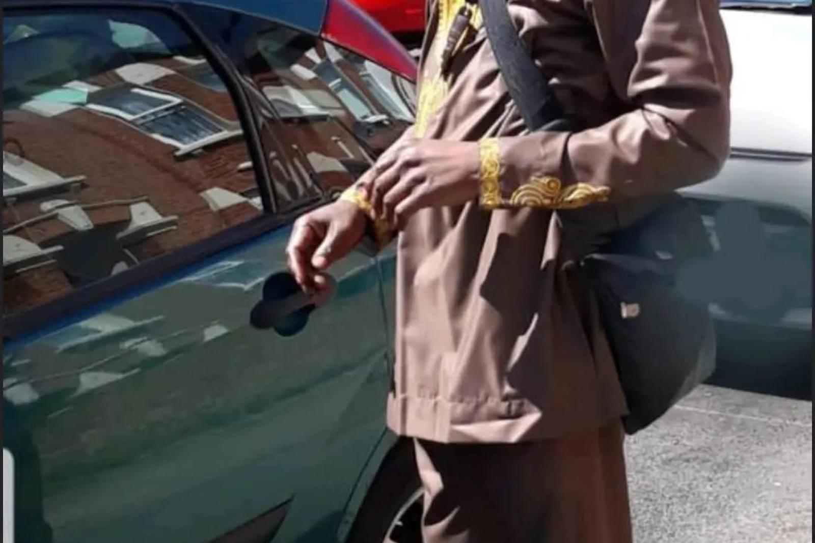 Fyah Mawi beside a car wearing a checked suit.